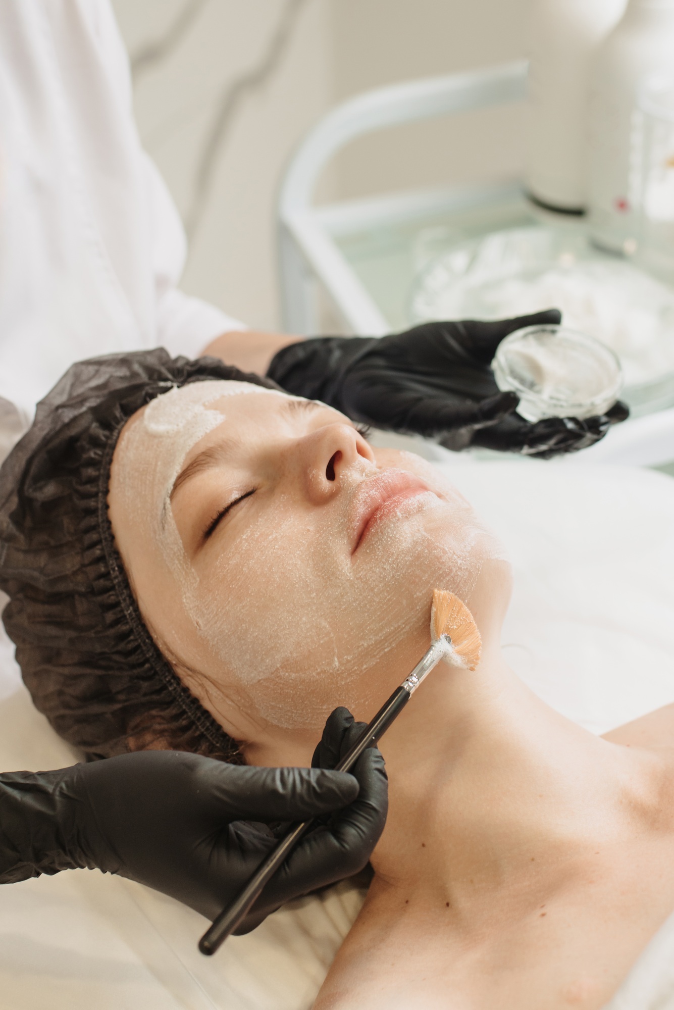 Facial peeling, spa treatments. A woman receiving facial care from a cosmetologist at a spa,close-up