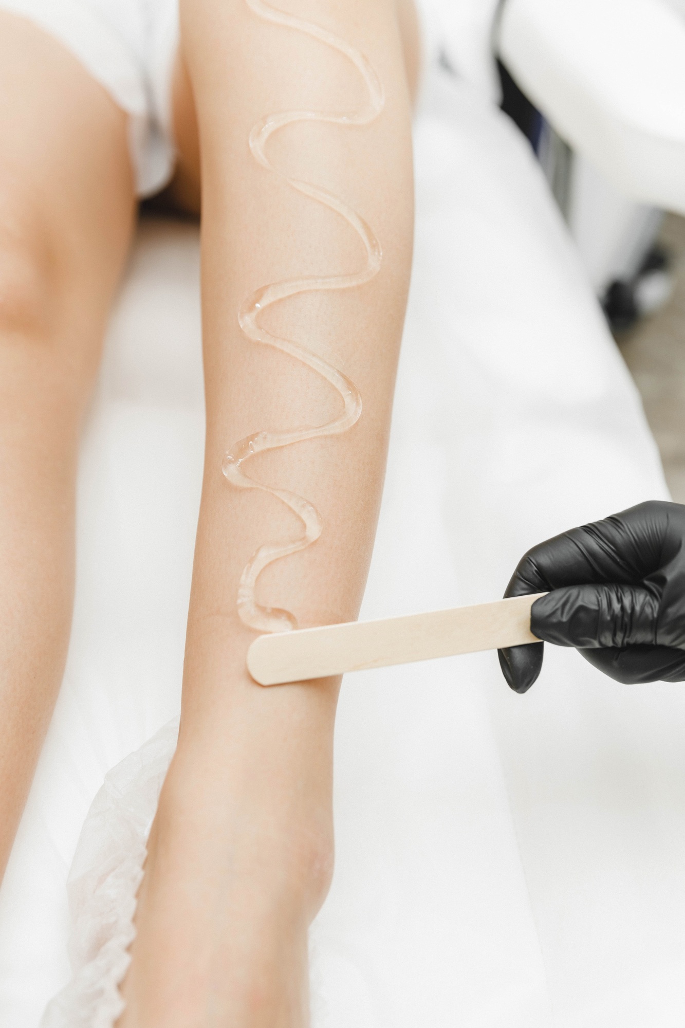 beautician applies gel for laser hair removal on smooth female legs. close-up. laser hair removal